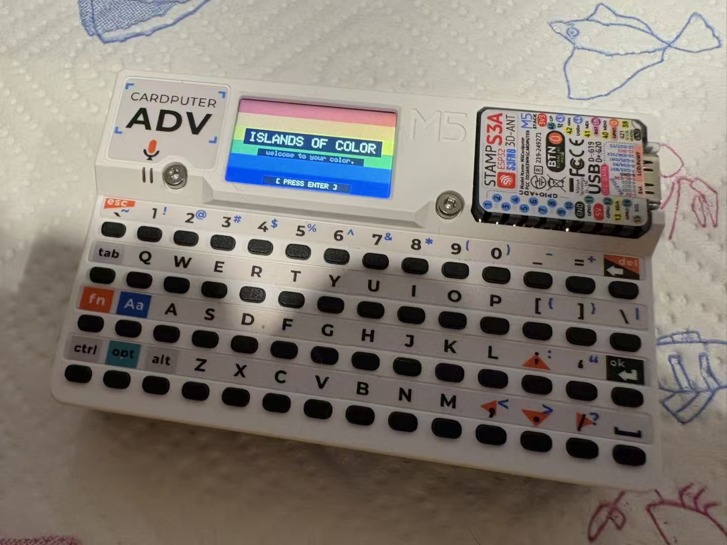 M5 Cardputer 显示 ISLANDS OF COLOR 欢迎屏,彩虹条纹横跨 240×135 像素